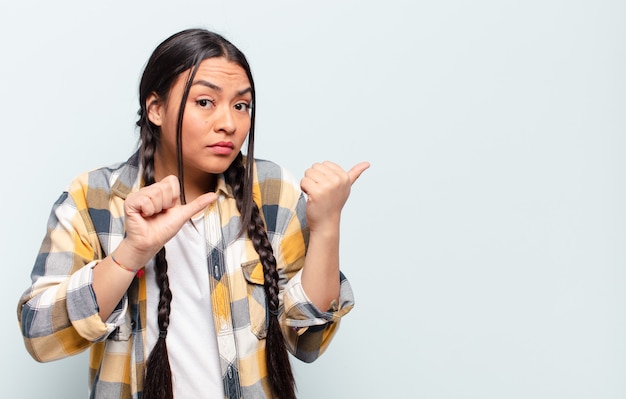 Young pretty hispanic woman with a copy space against isolated wall