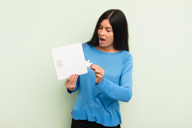 Young pretty hispanic woman with a puzzle