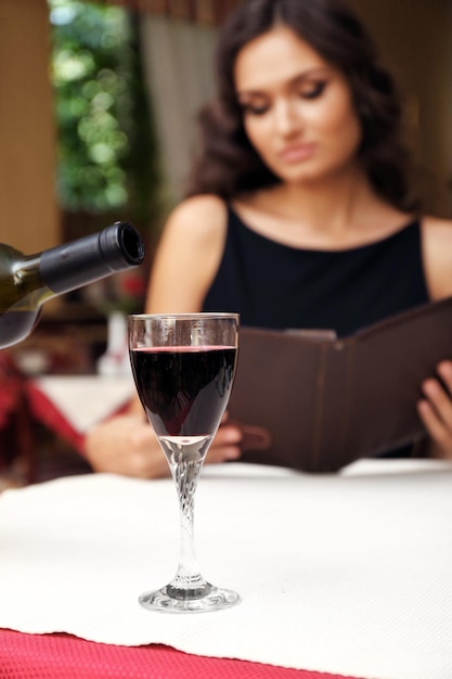 Young pretty lady at the restaurant. Waiter pouring wine in a glass