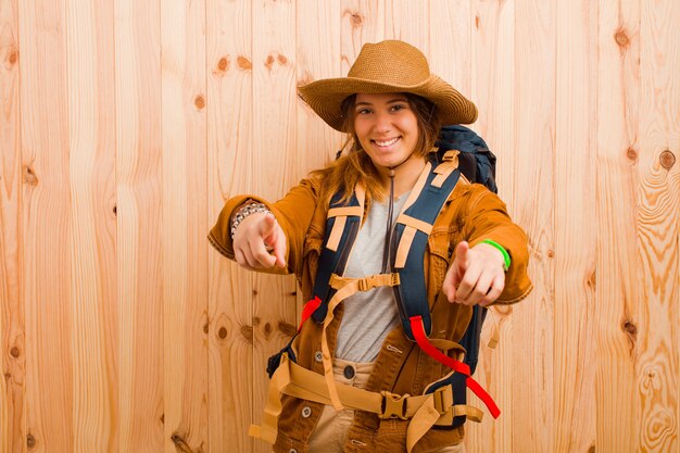 Young pretty latin traveler woman against wooden wall