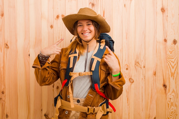 Young pretty latin traveler woman against wooden wall