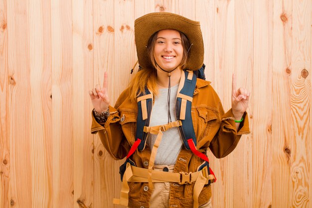 Young pretty latin traveler woman against wooden wall