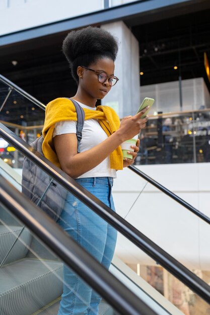 Young and pretty millennial woman on an escalator in a mall