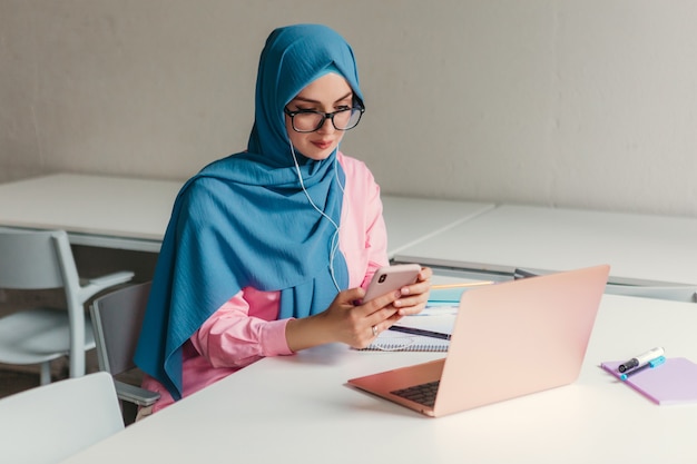 사무실 방, 온라인 교육에서 노트북에서 일하는 hijab에 젊은 꽤 현대 무슬림 여성