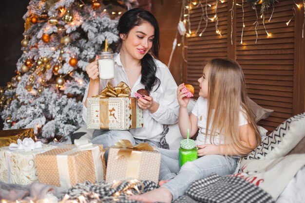 Giovane madre graziosa e sua figlia piccola che condividono i regali di natale