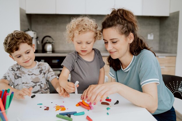 A young pretty mother is sitting at the kitchen table with her preschoolaged daughter and schoolaged