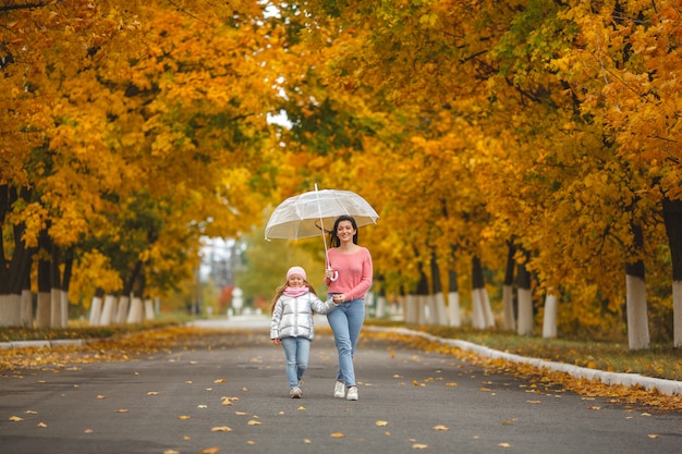 Young pretty mother with her little daughter having fun. Happy family in autumn