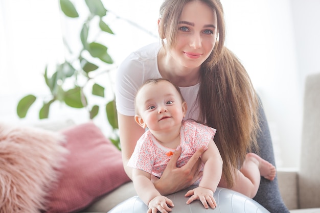 Young pretty mother working out with her little child at home