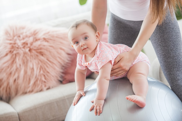 Young pretty mother working out with her little child at home