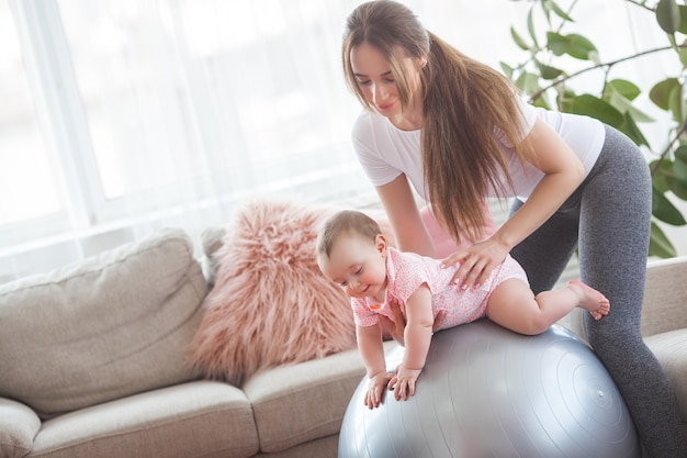 Young pretty mother working out with her little child at home