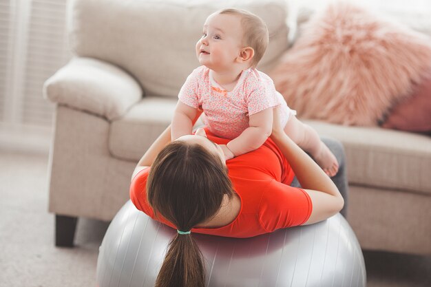 Young pretty mother working out with her little child at home