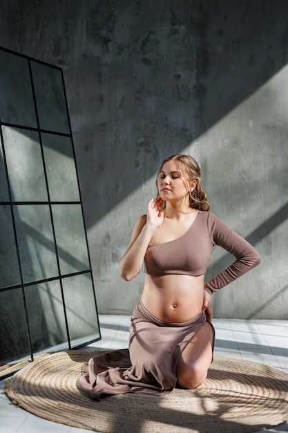 Young pretty pregnant woman in skirt posing in studio and stroking her belly Pregnant pregnant woman Happy pregnancy