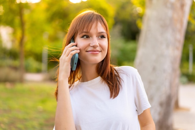 Giovane bella donna dai capelli rossi all'aperto usando il cellulare