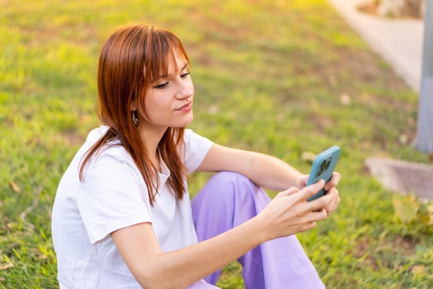 Young pretty redhead woman at outdoors using mobile phone