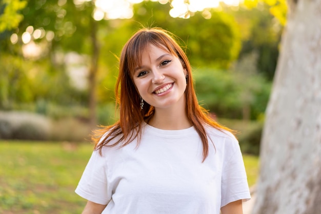 幸せな表情で屋外で若いかわいい赤毛の女性