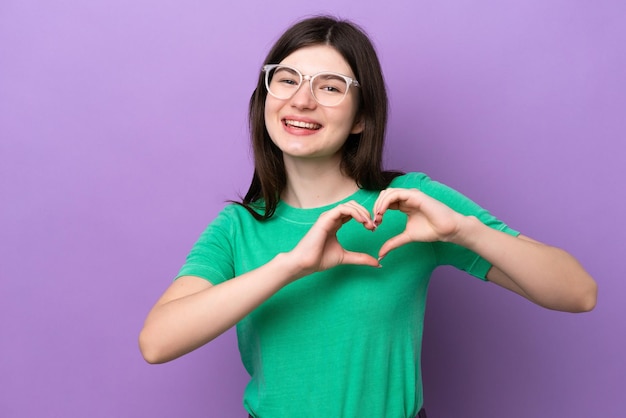 Young pretty Russian woman isolated on purple background With glasses making heart with hands