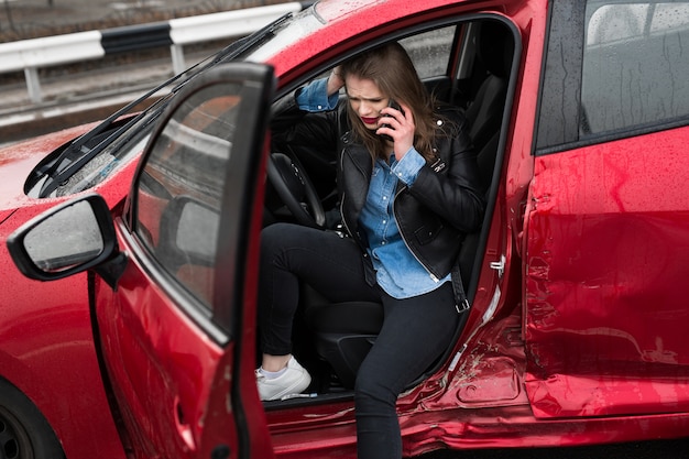 Young pretty scared woman in the car calls to a rescue service