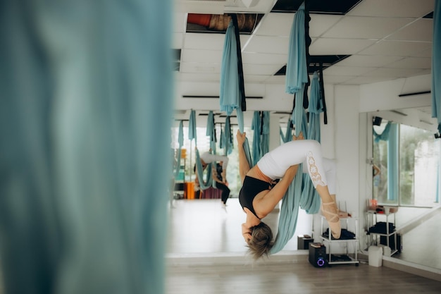 Young pretty slim body fitness girl practicing fly yoga in the gym High quality photo