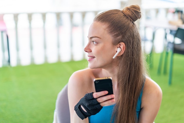 写真 屋外でバックポジションで携帯電話を使用して若いかなりスポーツ少女