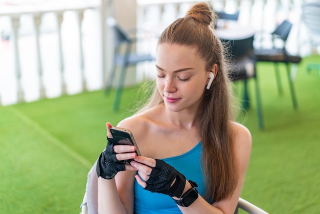 Young pretty sport girl using mobile phone at outdoors with happy expression