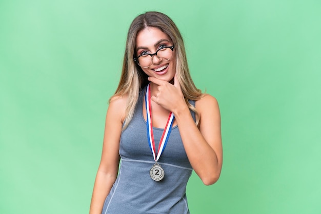 Young pretty sport Uruguayan woman with medals over isolated background with glasses and smiling