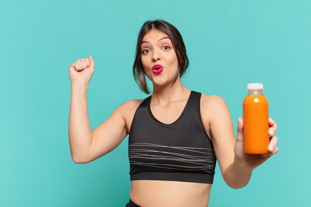 young pretty sport woman celebrating successful a victory and holding smoothy