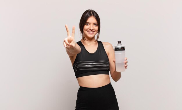 Young pretty sport woman celebrating successful a victory and holding a water bottle drink