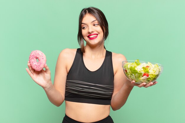 Young pretty sport woman doubting or uncertain expression and holding a salad