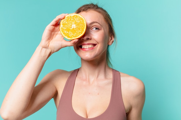 Young pretty sport woman happy expression and holding an orange