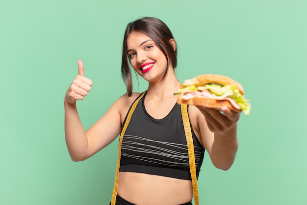 Молодая красивая спортивная женщина счастливым выражением и держит бутерброд
