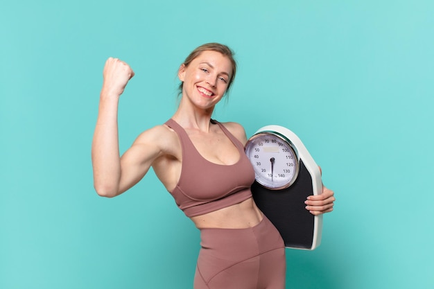 Young pretty sport woman happy expression and holding a weight scale