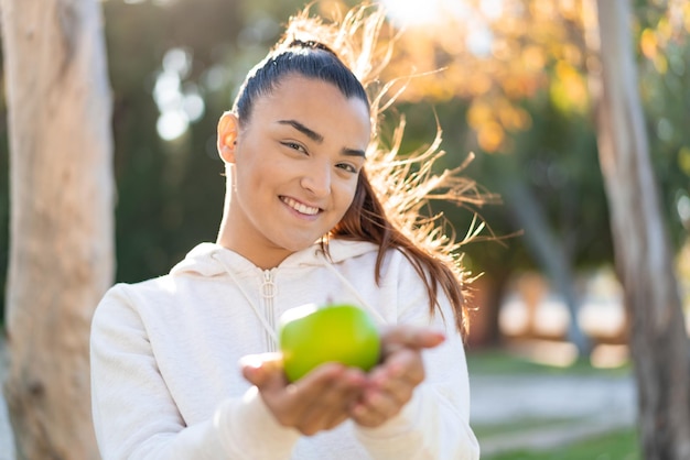 Photo young pretty sport woman holding an apple with happy expression