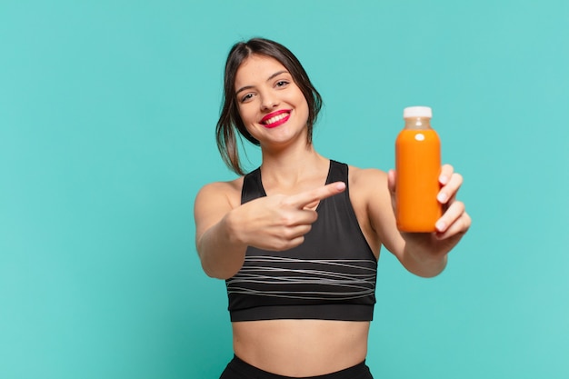 Young pretty sport woman pointing or showing and holding smoothy