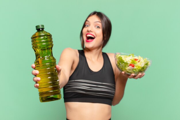 Молодая красивая спортивная женщина удивлена выражением лица и держит салат