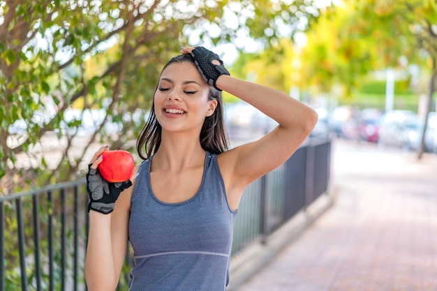 Young pretty sport woman with an apple at outdoors has realized something and intending the solution