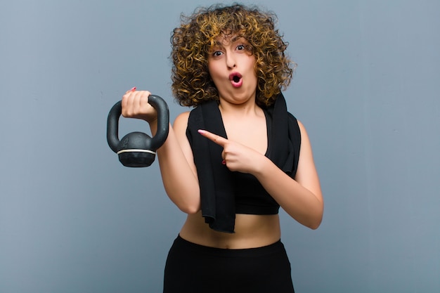 Young pretty sports woman wearing fitness clothes lifting a dumbbell