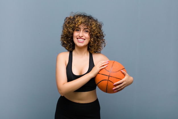 Young pretty sports woman wearing fitness clothes with a basket ball