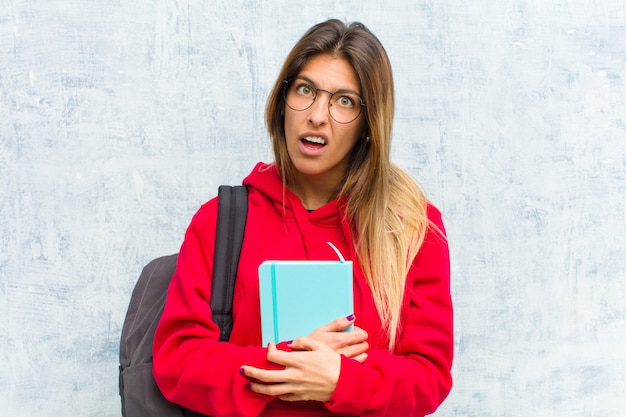 Foto la giovane studentessa carina si sente perplessa e confusa, con un'espressione stupida e sbalordita guardando qualcosa di inaspettato