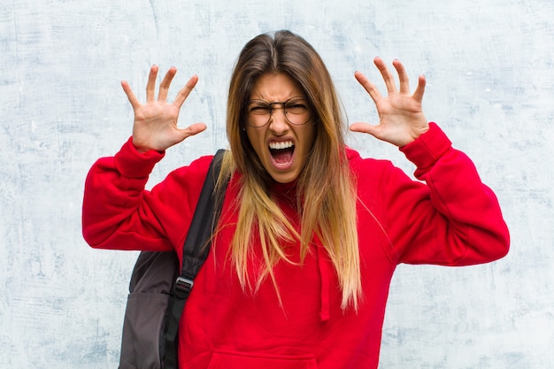 Photo young pretty student screaming in panic or anger, shocked, terrified or furious, with hands next to head