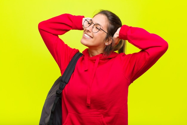 Young pretty student smiling and feeling relaxed, satisfied and carefree, laughing positively and chilling