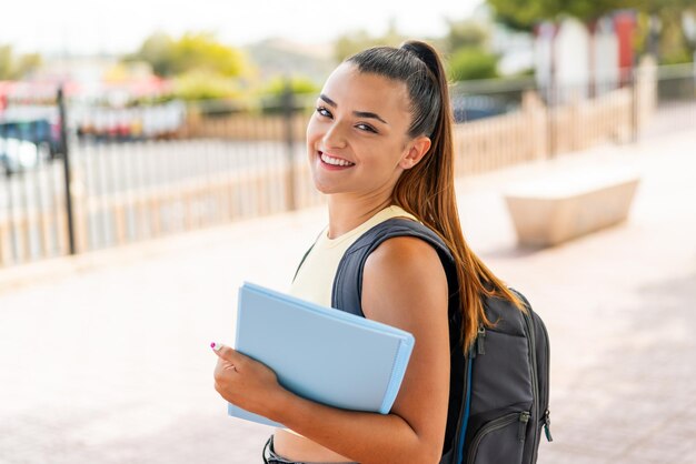 Young pretty student woman at outdoors smiling a lot