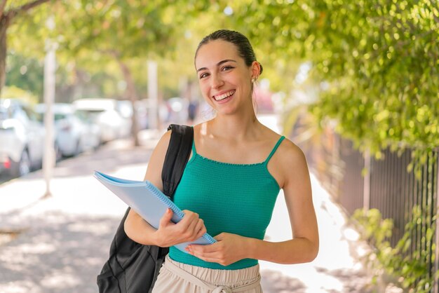 Young pretty student woman at outdoors smiling a lot