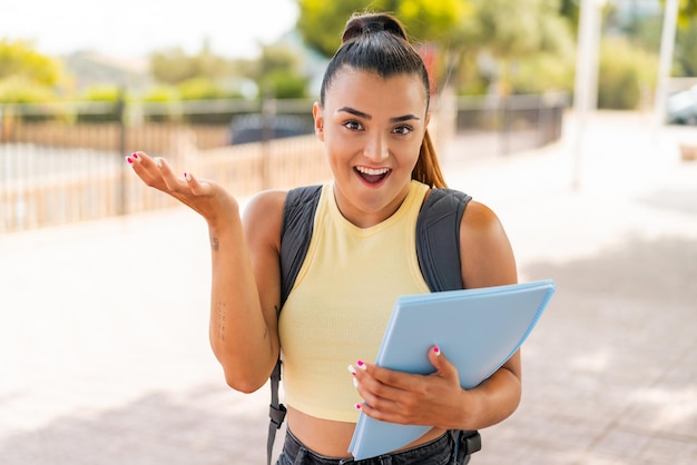 ショックを受けた表情で屋外で若いかわいい学生女性