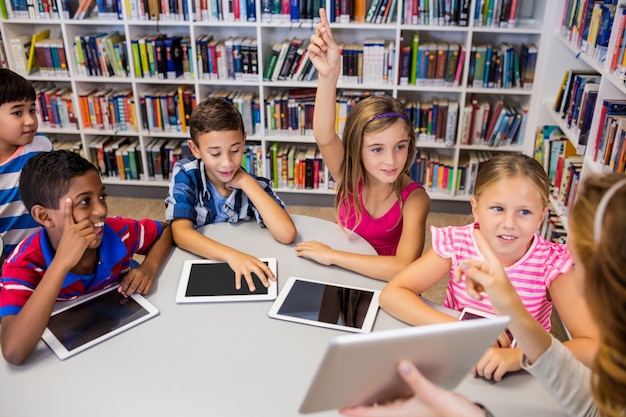 Young pretty teacher having lesson to children with their tablet