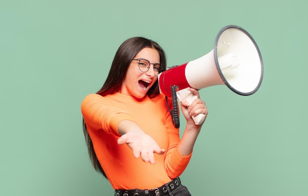 Young pretty teenager girl. shocked or surprised expression. megaphone concept