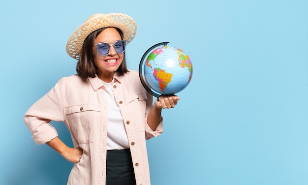 世界の地球地図を持つ若いきれいな旅行者の女性。旅行や休日のコンセプト