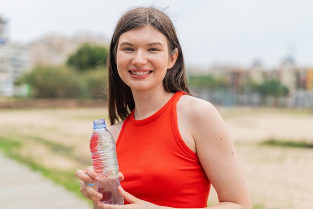 Young pretty Ukrainian woman with a bottle of water at outdoors