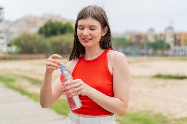 Young pretty Ukrainian woman with a bottle of water at outdoors