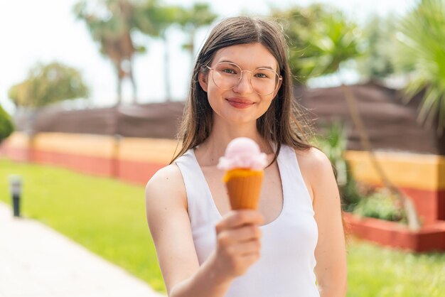 屋外で幸せな表情でコルネットアイスクリームを持つ若いかなりウクライナの女性