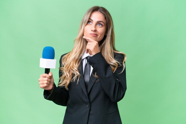 Young pretty Uruguayan tv presenter over isolated background having doubts while looking up